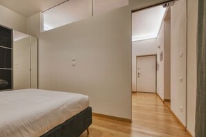 Ein Schlafzimmer mit Bett, Kleiderschrank, Spiegel und einer Tür zu einem anderen Raum.