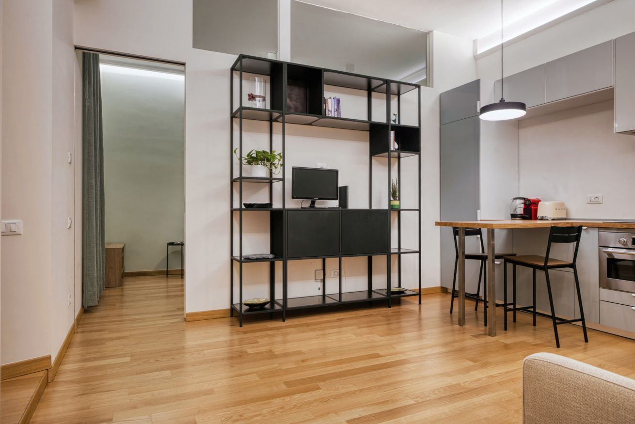 Eine moderne Küche mit Holzausziehtisch, einem schwarzen Metallregal und einem Essbereich mit zwei Stühlen.