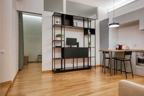 Eine moderne Küche mit Holzausziehtisch, einem schwarzen Metallregal und einem Essbereich mit zwei Stühlen.