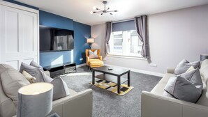 Un salon moderne comprenant un canapé, une table basse, un téléviseur et un fauteuil.