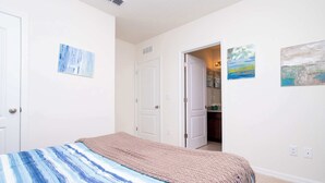 Een slaapkamer met een bed, een deur en een gang naar een andere kamer.