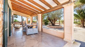 Une terrasse extérieure dotée d’une pergola en bois, d’une table avec des chaises et offrant une vue sur le paysage environnant.