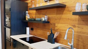 A modern kitchen with a built-in stove, stainless steel sink, and wooden wall paneling. - Beautiful art deco apartment (Sehmatal)