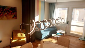 A modern living room with a sofa, a dining table, and a unique circular light fixture. - Beautiful art deco apartment (Sehmatal)