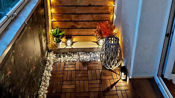 A cozy corner with a wooden wall, string lights, and potted plants. - Beautiful art deco apartment (Sehmatal)