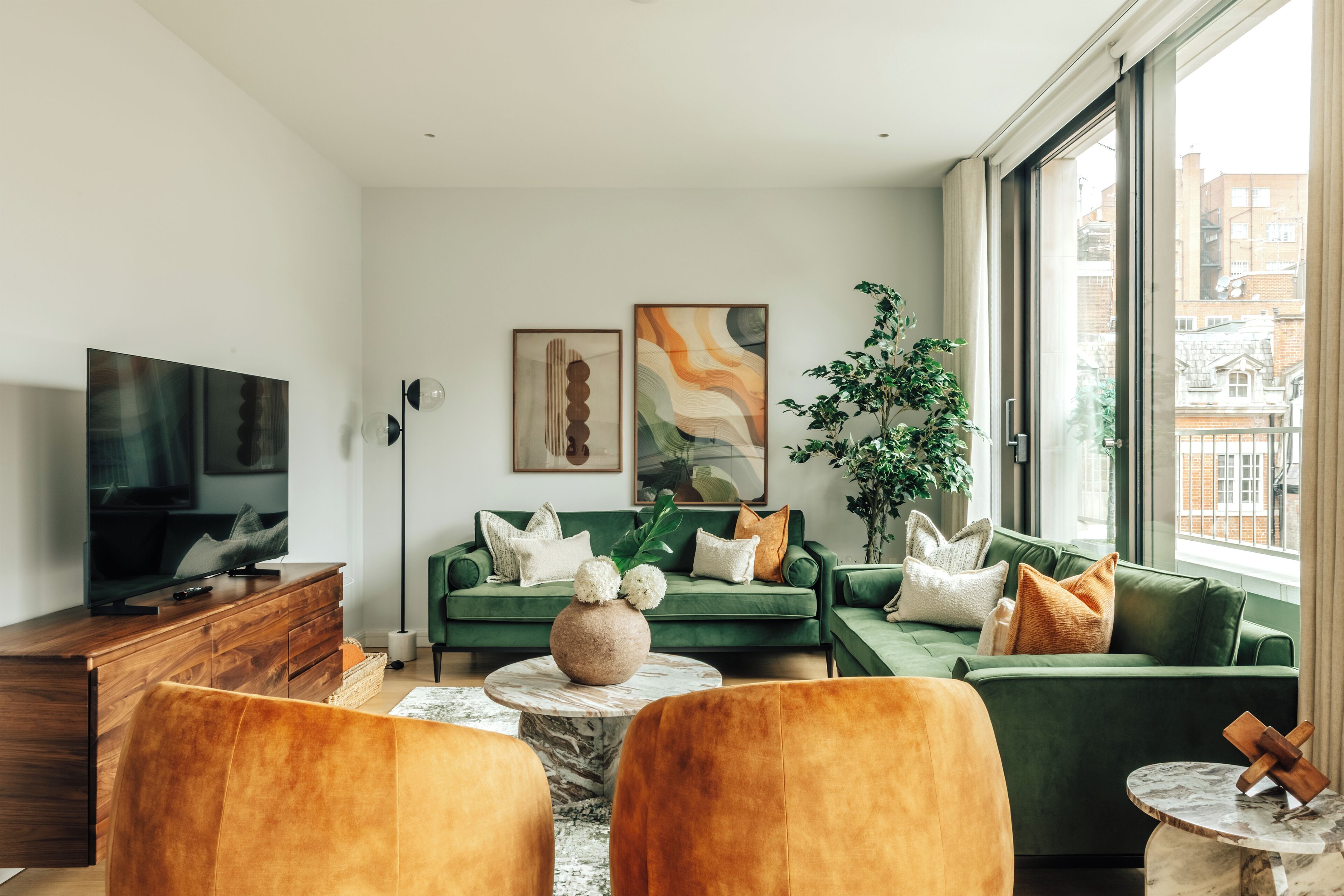 A modern living room with a green sofa, a wooden coffee table, and a television on a wooden cabinet.