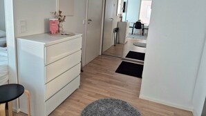 A modern hotel room with a white dresser, a small round table, a mirror, and a wooden floor. - M&J Apartments Harbour (Jyväskylä)