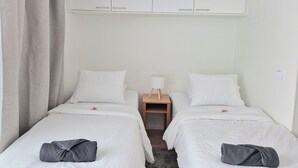 A twin room with two beds, a wardrobe, a nightstand, and a lamp. - M&J Apartments Harbour (Jyväskylä)