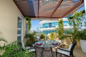 A covered outdoor seating area with a round table, chairs, and potted plants. - Sleeps 6 Views Beach 1 Block Gated (Nuevo Nayarit)