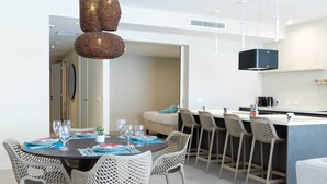 A modern dining area with a round table, white wicker chairs, and a bar area with stools. - The Wharf 5A in Willemstad (Willemstad)