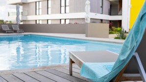 A poolside area with a lounge chair and a wooden deck. - The Wharf 5A in Willemstad (Willemstad)