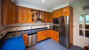 Une cuisine avec des meubles en bois, des appareils en acier inoxydable et un plan de travail bleu.