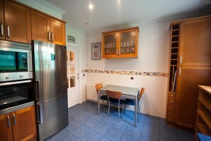 Une cuisine compacte dotée de meubles en bois, d’un réfrigérateur en acier inoxydable, d’un four à micro-ondes et d’une table à manger avec des chaises.