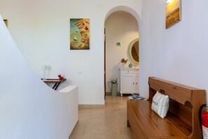 A hallway with a wooden bench, a white cabinet, and a painting on the wall. - Villa 'Ingrosso' with Sea View, Wi-Fi and Air Conditioning (Leporano Marina)