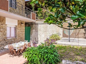 Une cour intérieure avec une table à manger dressée pour quatre personnes, entourée de verdure et agrémentée d’un hamac.