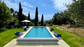 Une piscine rectangulaire à l’eau d’un bleu limpide, entourée d’une terrasse dallée et d’une pelouse.