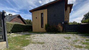 Een modern huis met twee verdiepingen, een houten buitenkant en een donkere metalen gevel.