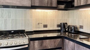 Een keuken met donkere houtkasten, een Gafa kooktoestel, een koffiezetapparaat en een broodrooster.