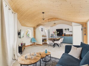 A cozy living room with a high wooden ceiling, a dining area with a TV, and a kitchen with blue cabinets. - House for 6 with garden, near salt marshes (L'Epine)