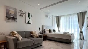 Un salon moderne avec un canapé gris, un grand lit et un sol en marbre.