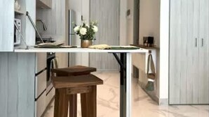 Une cuisine moderne avec des meubles blancs, une table en bois et un vase rempli de fleurs.