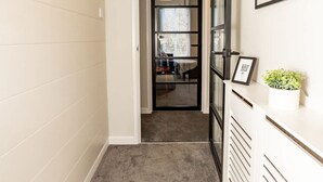 Un pasillo con piso alfombrado, un radiador blanco y un cuadro en la pared.