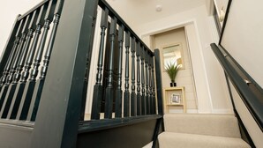 Una escalera con barandillas negras y un rellano cubierto de moqueta beige.