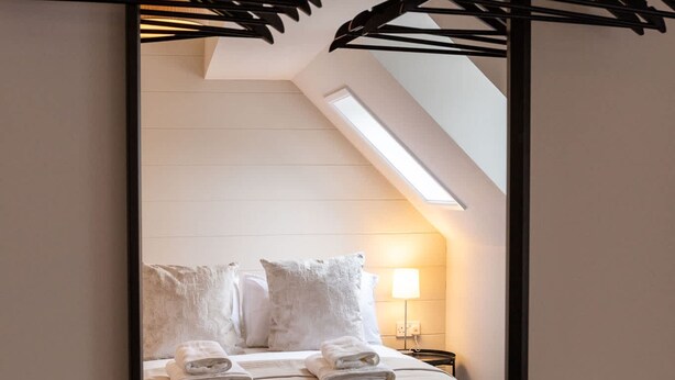 Un dormitorio con cama, almohadas, lámpara y luz en el techo.