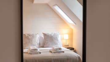 A bedroom with a bed, pillows, a lamp, and a ceiling light.