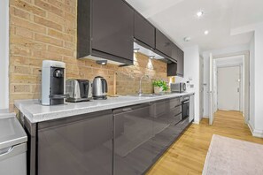 Eine moderne Küche mit Backsteinwand, Edelstahlgeräten und Holzboden.