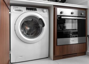 A compact washer and dryer unit with a control panel, integrated into a wooden cabinet. - Stayshort - Cozy Modern 1BR Sleeps 4 With Burj Views (Dubai)
