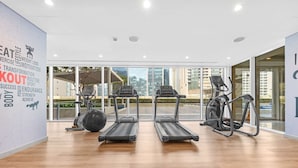 Un gimnasio moderno con cintas de correr, elípticas y una máquina de remo.