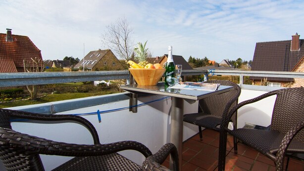 Une terrasse sur le toit, avec des fauteuils en osier, une table et un panier de fruits.