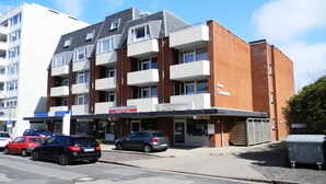 A multi-story building with a brick facade, multiple balconies, and a ground-level entrance with a sign. - Hyggelige vacation apartment with swimming pool and sauna in Haus Ornum in Westerland (Westerland)
