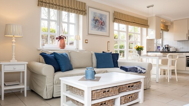 Een moderne woonkamer met een bank, salontafel en een eethoek met stoelen.