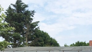 Ein Backsteinhaus mit einer Terrassenanlage, die einen gestreiften Stuhl, einen runden Tisch und ein Fenster mit weißem Rahmen zeigt.