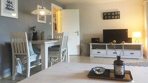 Ein modernes Wohnzimmer mit Essbereich, einem Fernseher und einem dekorativen Schild an der Wand.