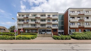 A modern multi-story building with balconies, a driveway, and a clear sky. - Modern vacation apartment with sauna and heated indoor pool in Westerland (Westerland)