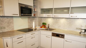 A modern kitchen with white cabinets, a built-in oven, and a coffee maker. - Modern vacation apartment with sauna and heated indoor pool in Westerland (Westerland)