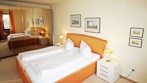 A hotel room with a large bed, a bedside table with a lamp, and framed pictures on the wall. - Modern vacation apartment with sauna and heated indoor pool in Westerland (Westerland)