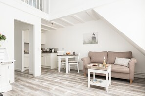 A modern loft-style apartment with a dining area, kitchenette, and a living room with a sofa and coffee table. - Comfortable vacation apartment in Westerland with modern furnishings and parking space (Westerland)