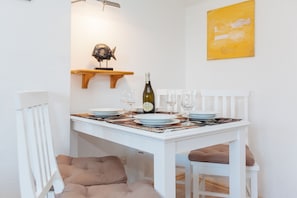 A dining table set with plates, glasses, and a bottle, with a fish decoration on a shelf above. - Comfortable vacation apartment with garden and terrace (Wenningstedt)