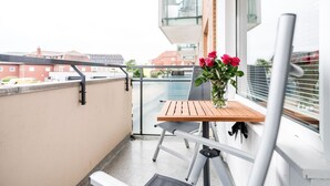 A balcony with a wooden table, a chair, and a vase with flowers. - Modern vacation apartment with sauna, solarium and heated indoor pool in Westerland (Westerland)