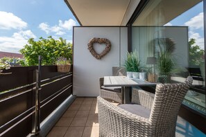 Ein Balkon mit Korbmöbeln, einer herzförmigen Dekoration und Topfpflanzen.