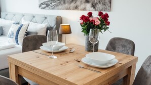 Ein Esstisch gedeckt mit Tellern, Besteck und einer Blumenvase.