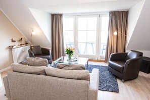 A modern living room with a sofa set, a coffee table, and a fireplace. - Beautiful vacation apartment with sauna, indoor pool and fitness room in Keitum (Keitum)