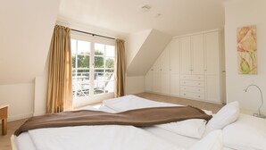 A bedroom with a large bed, a wardrobe, and a window with curtains. - Beautiful and modern house in Alt- Westerland (Westerland)