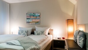 Ein ordentlich eingerichtetes Schlafzimmer mit Bett, Nachttischen, einer Nachttischlampe und einem Wandbild.