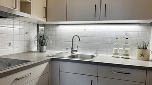 Eine moderne Küche mit Spüle aus Edelstahl, weißen Schränken und einem eingebauten Herd.