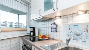 A modern kitchen with white cabinets, a stainless steel sink, and a window with a white valance. - Comfortable 2-room vacation apartment in the Nordmarkhof with balcony in Westerland (Westerland)